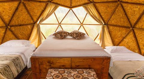 Interior del domo geodésico acondicionado para 4 personas, con ventanal y vista a la montaña