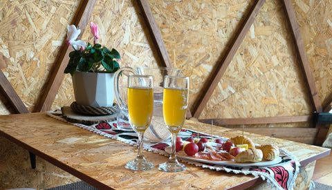 Snack incluido en la decoración dentro del domo, con dos copas de vino de gulupa de la casa y ambientado con flores naturales.